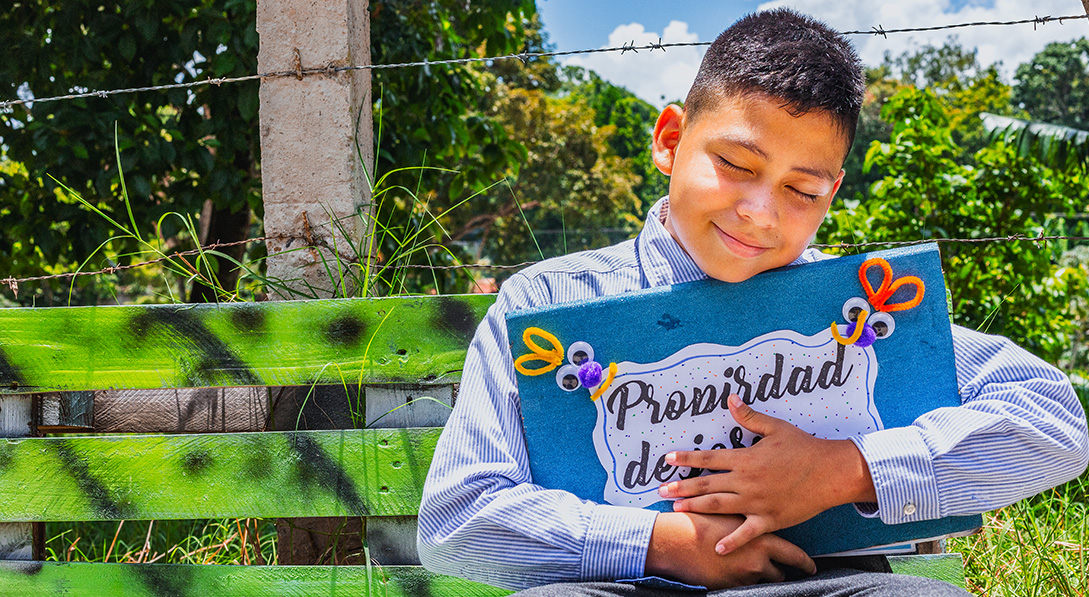 Josué holds a folder that he made for his sponsor's letters