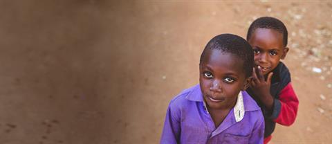 A boy sits on a rock outside