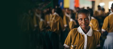 A student smiles towards the camera in a classroom of students