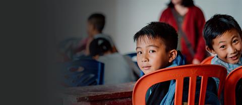 Two boys smile at the camera in a classroom