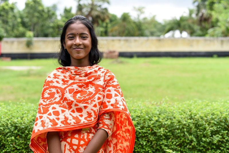 A girl smiles while standing outside her child development center