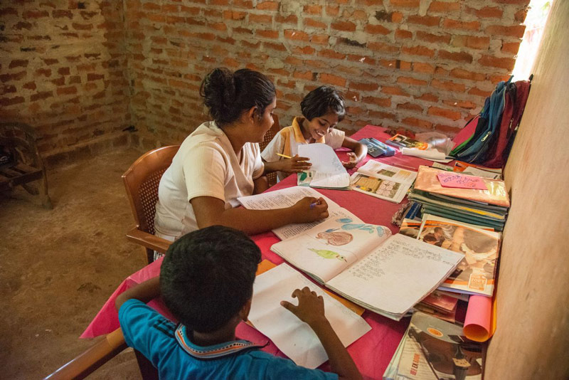 An older sister helps her siblings do their homework