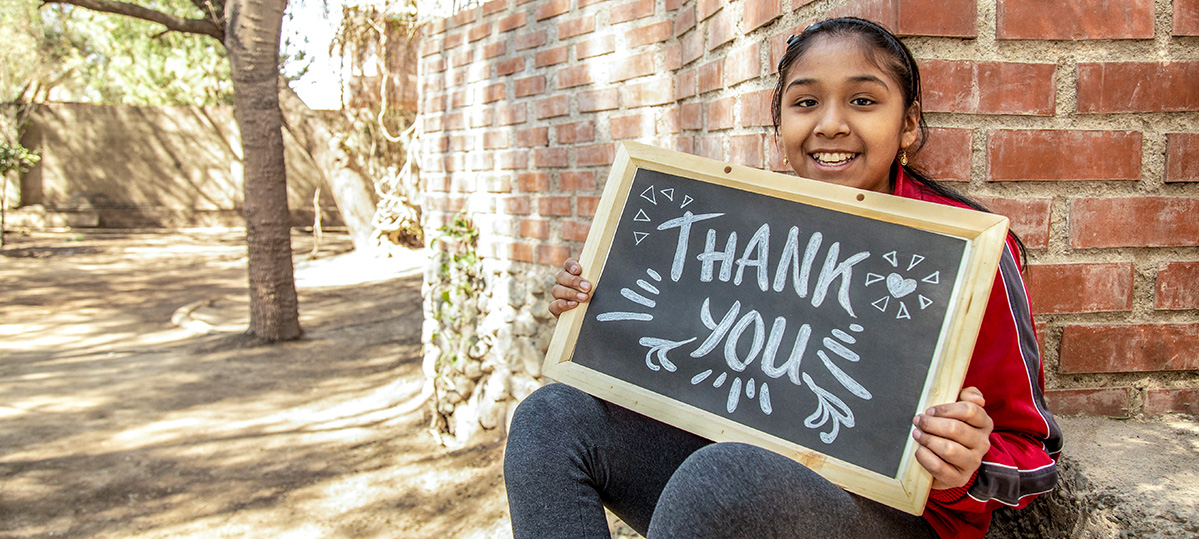 A girl holds a sign that says Thank You