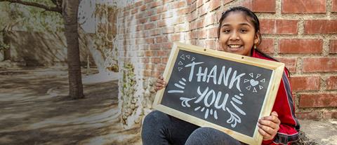 a girl holds a sign that says "Thank You"