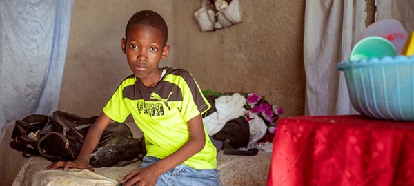 boy in a neon green shirt sitting on his bed