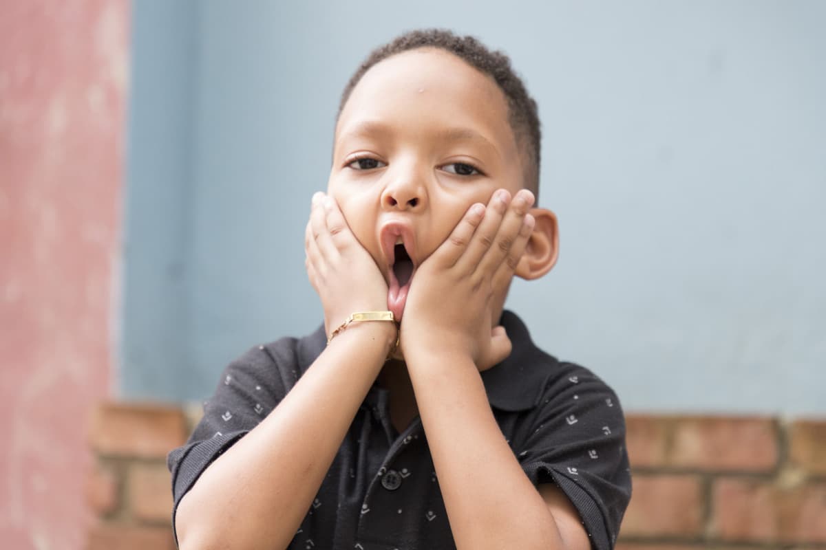 Boy with both hands on his face smushing his cheeks making a funny face.