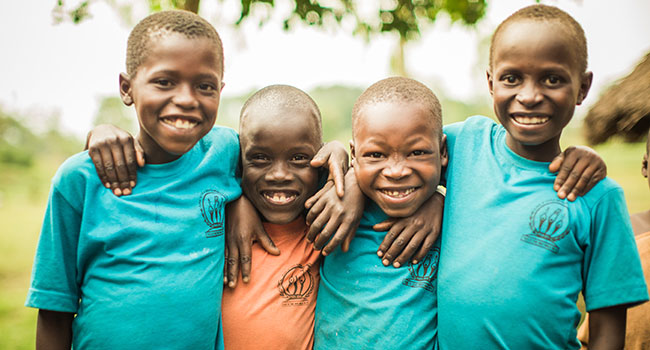 Boys standing next to each other with arms around each other smiling wearing school uniforms