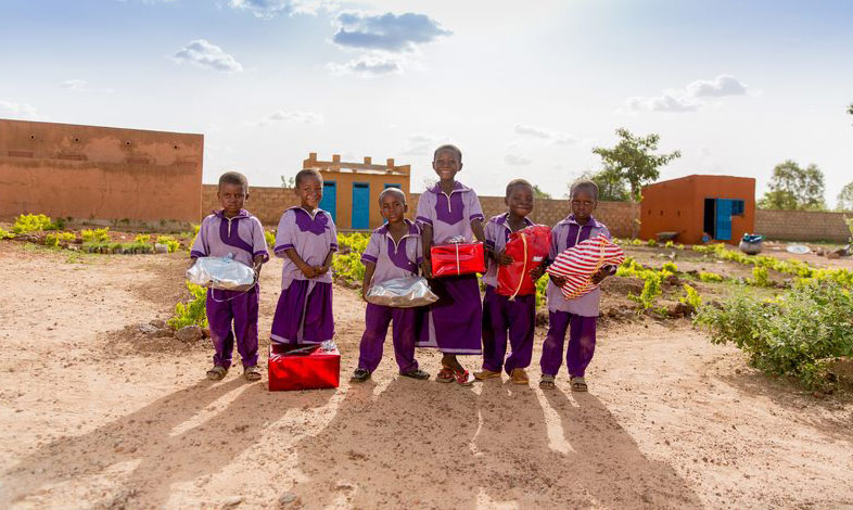 Young children smile while holding Christmas gifts