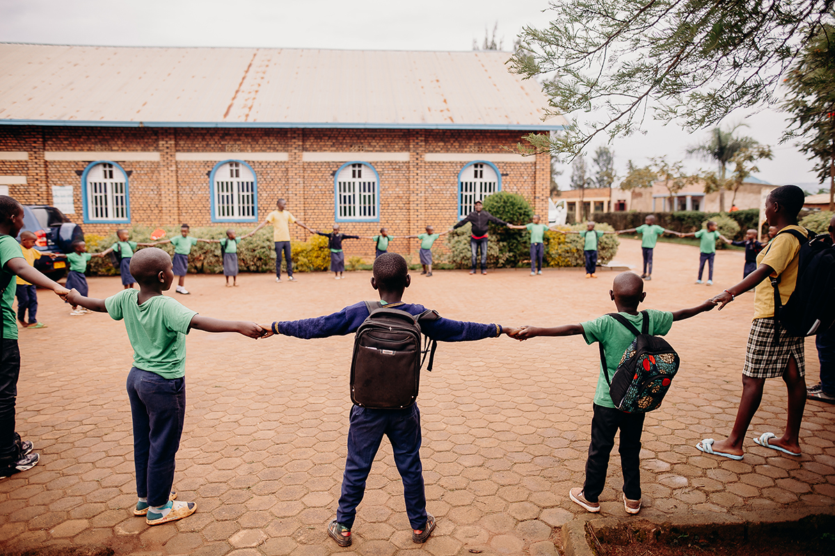  group of children hold hands in a large circle in front of their church.