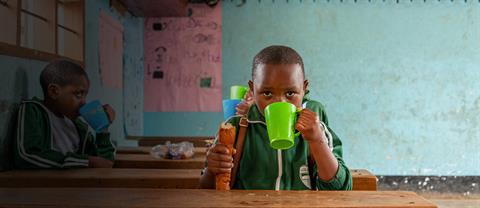 A boy sitting and drinking out of a cup