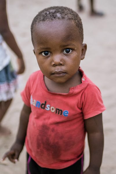 young child wearing a red shirt looking at the camera