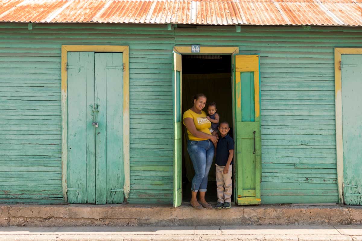 A mother stands in the doorway of her home with her two children