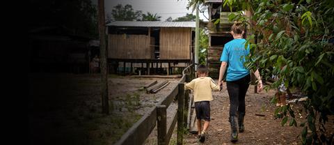 A sponsor walking with a child and hodling hands