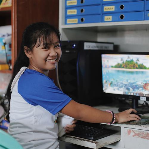 Smiling girl learns to use a computer.