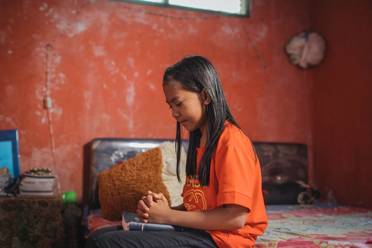 Tivani prays on her bed