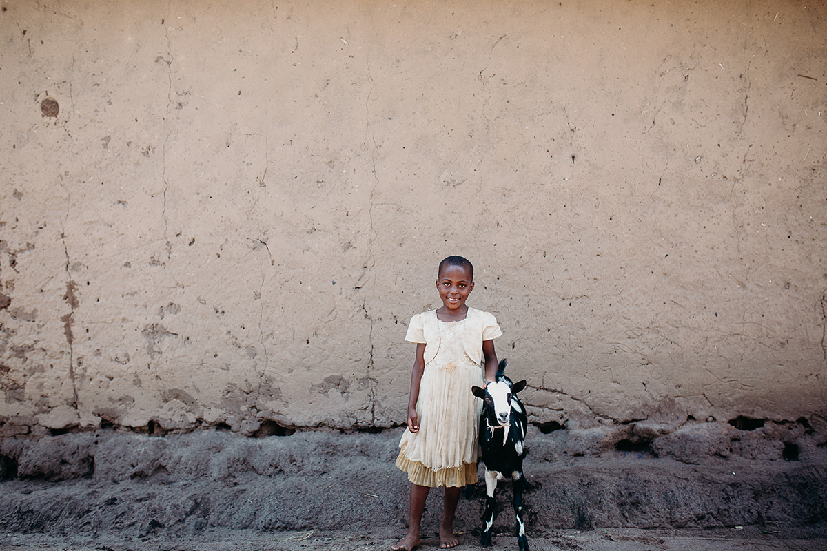 a girl stands with a goat