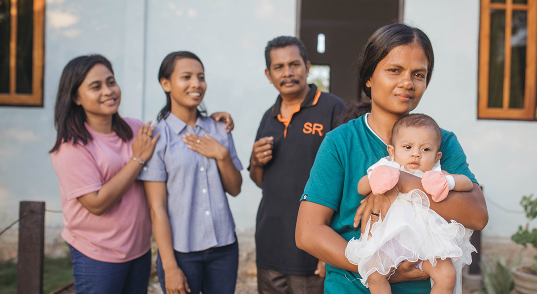 Barbalinda holds Adiva while the pastor and staff stand behind