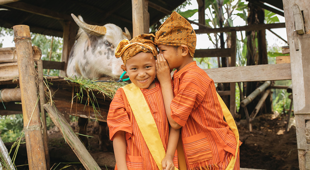 two boys smile and whisper to each other