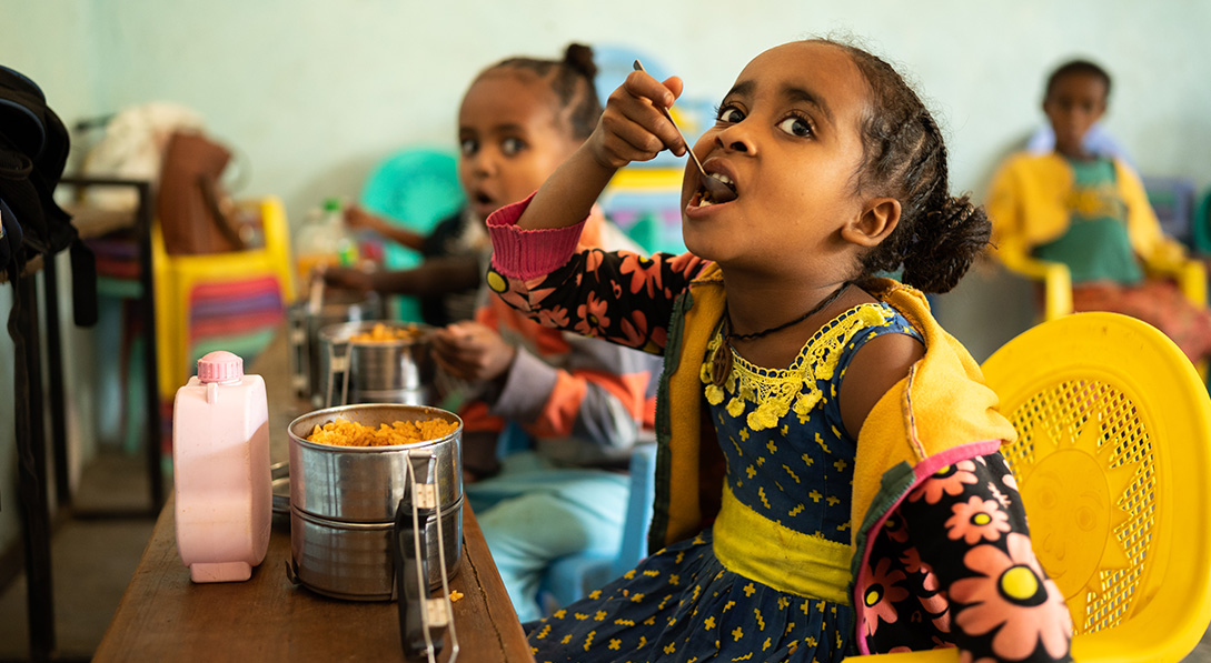 2 young girls eat lunch at their school