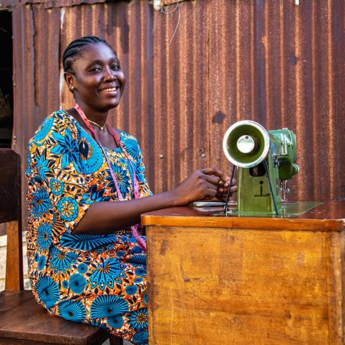 a woman sits at a sewing machine