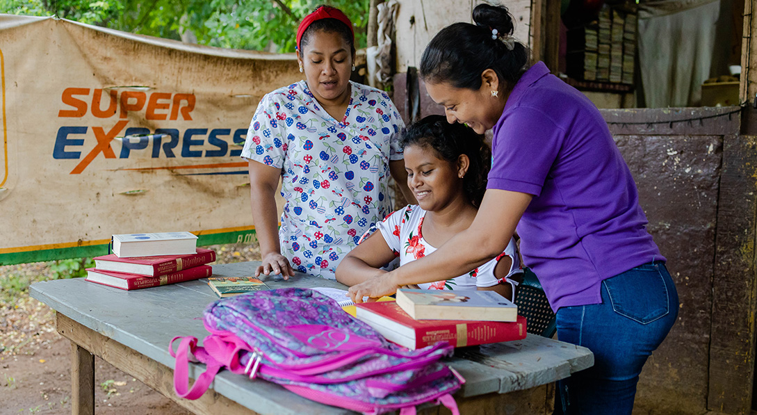 Crisli's center director, Greyner, and tutor, Marjali, help her with homework