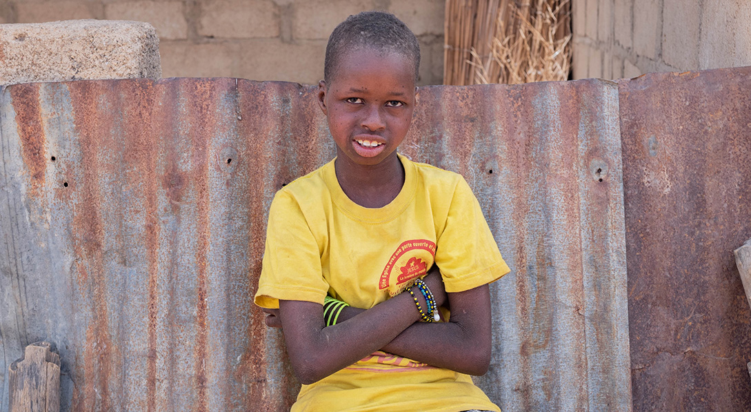 Awa sits near her house