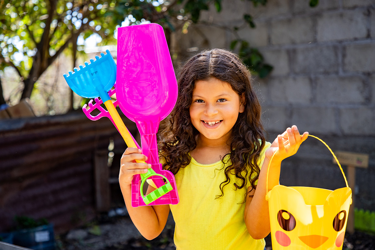 Valeria holds up her gardening tools