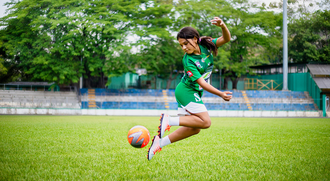 Karla jumps and kicks a ball