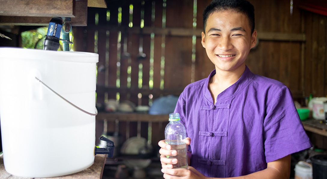 child in front of water filter with water bottle