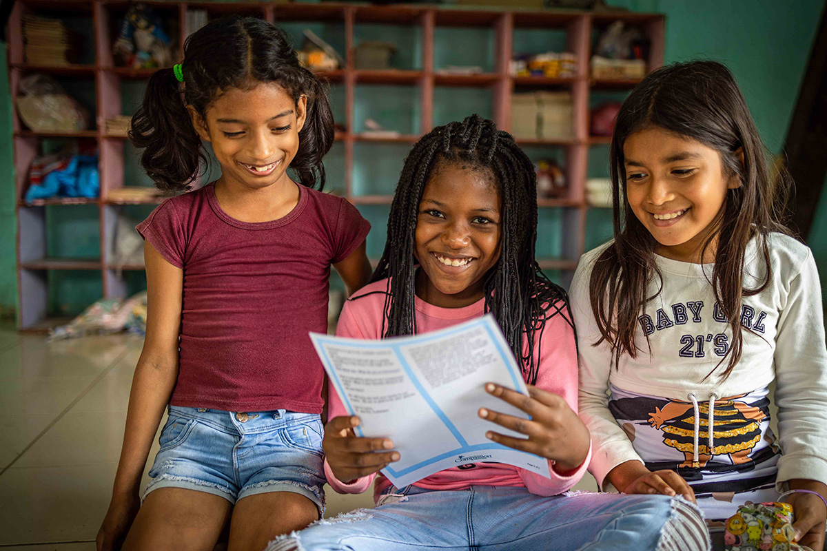 Three children reading a sponsored letter.