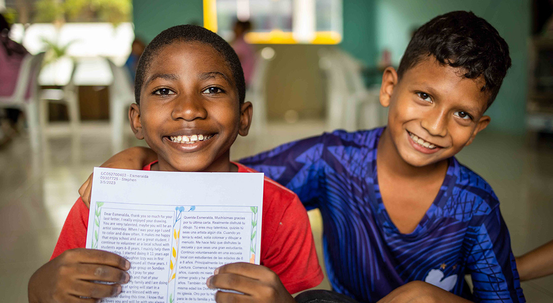 Two children with one holding a sponsored letter.