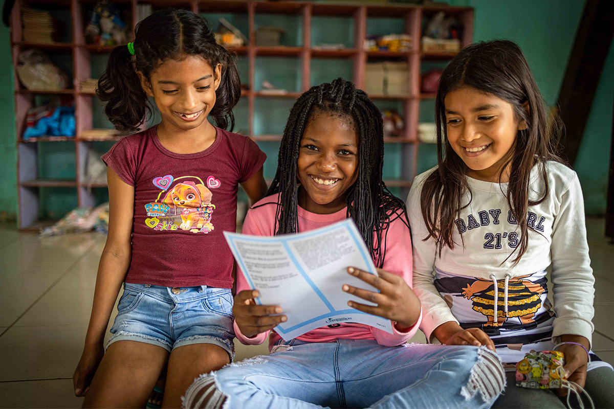 girls hold letter and smile