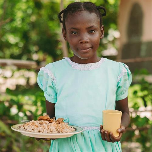 child looking at camera with plate and cup