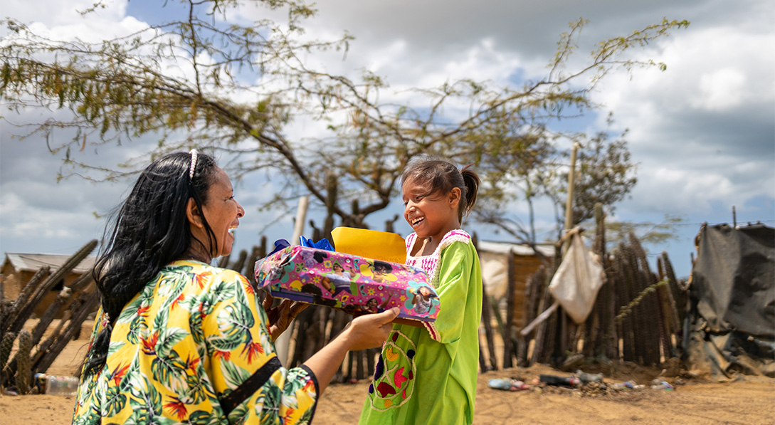 woman gives gift to smiling little girl