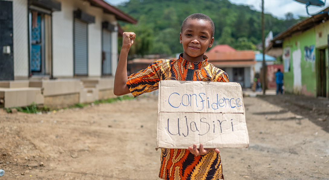 Jovine holds sign that says "confidence" in Swahili