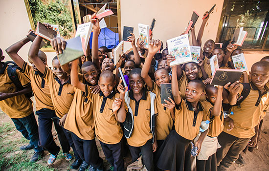 A group of children standing together and holding books above their heads