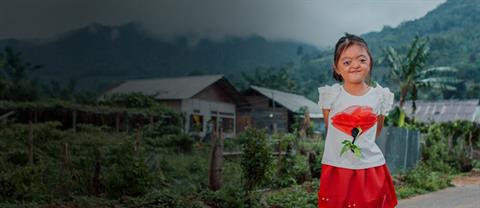 A girl smiles and stands outside