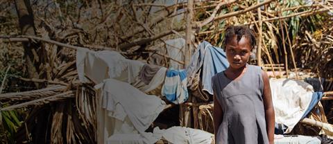 A girl stands in front of debris