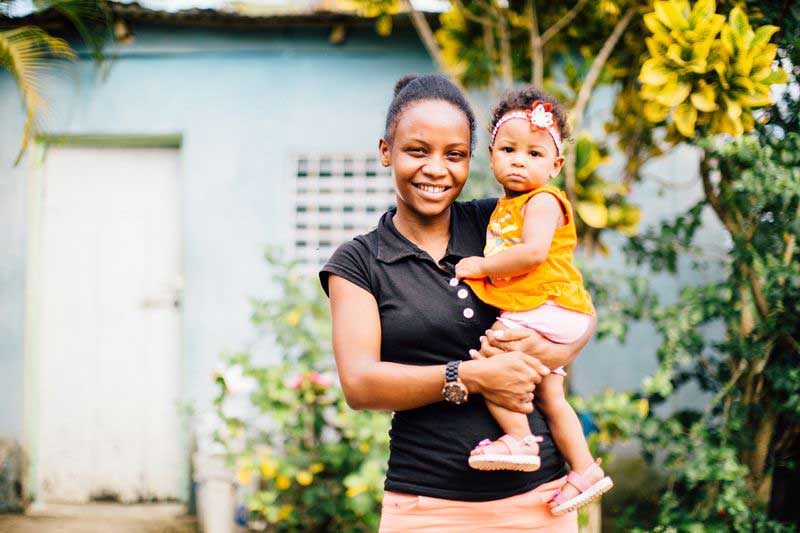 A mother smiles and holds her baby