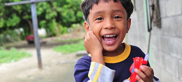 A young boy smiles while holding a toy car