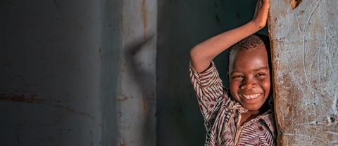 A young boy smiling against a wall