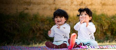 Twin baby girls sitting on a blanket