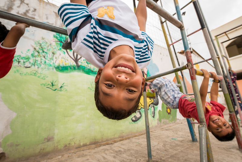 Children hang on the playground equipment at their child development center