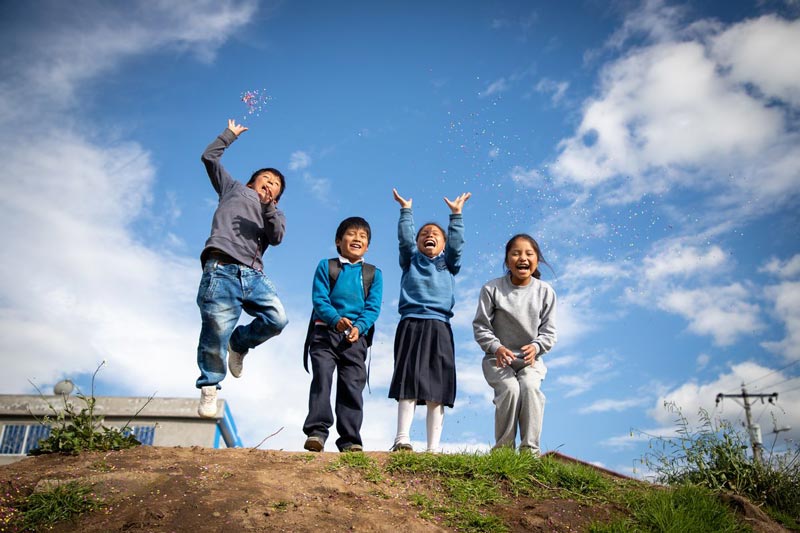 Children laugh as they throw confetti into the air