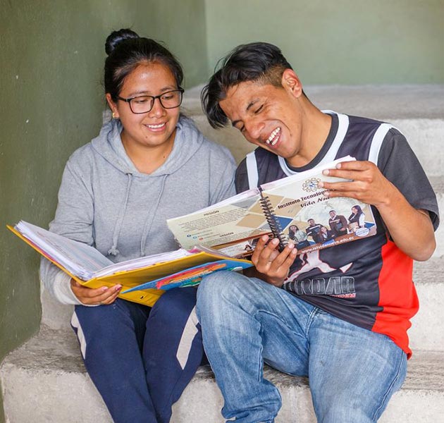 A girl and boy sit together on steps and read books