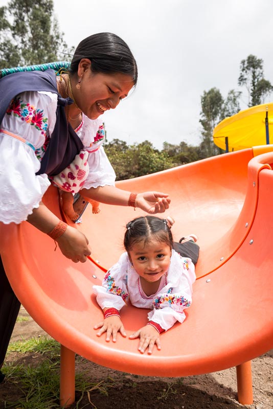 A young girl slides on her stomach on the playground at her child development center