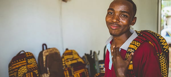 A teenage boy smiles with a backpack on