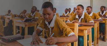 A boy sitting at a desk in a classroom working on some papers