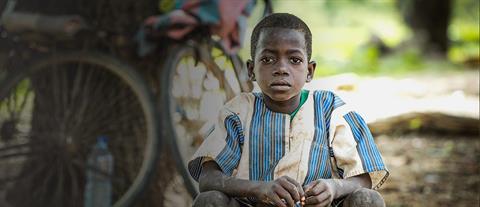 A solemn looking boy in a blue and white vertically striped shirt