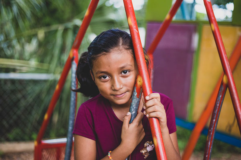 A girl sits on a swing at the playground